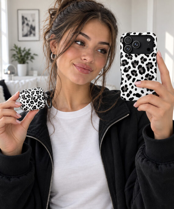 Woman holding a matching black-and-white leopard phone case and AirPods case Title: Matching Leopard Phone & AirPods Cases